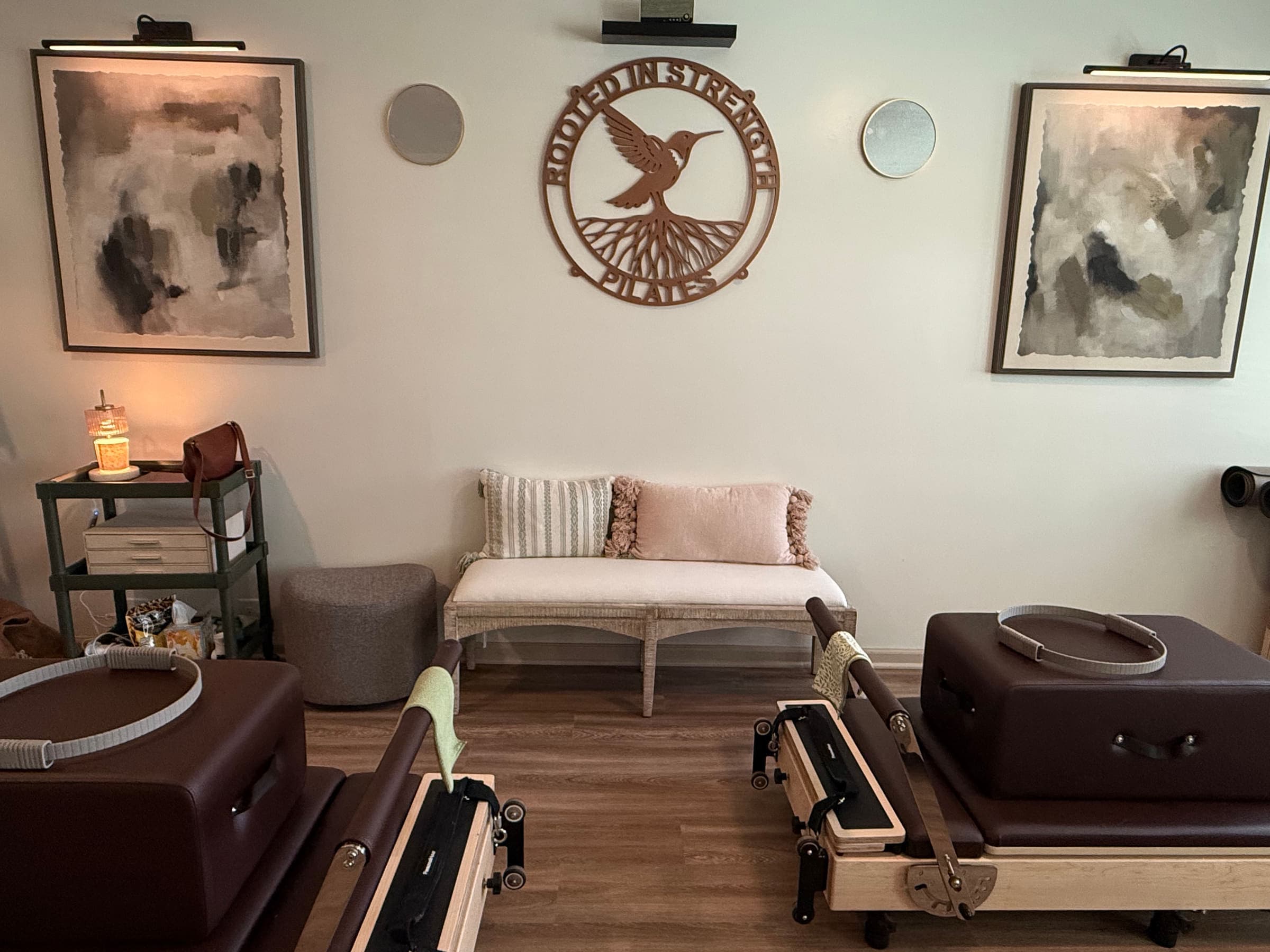 Reformers and a bench beneath the Rooted in Strength Pilates wall sign in the Seaford, DE studio